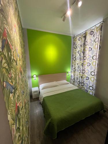 ein grünes Schlafzimmer mit einem Bett und einer grünen Wand in der Unterkunft H Rooms boutique Hotel in Neapel