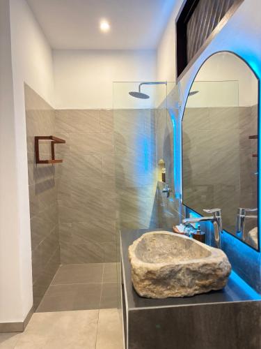 a bathroom with a stone sink and a mirror at White Seeds Boutique Villas in Gili Trawangan
