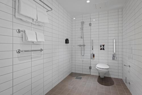 a white tiled bathroom with a toilet and a shower at Home Hotel Astoria in Hamar