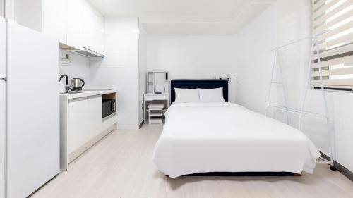 a white bedroom with a large bed and a kitchen at Yeosu Onueli Pension in Yeosu