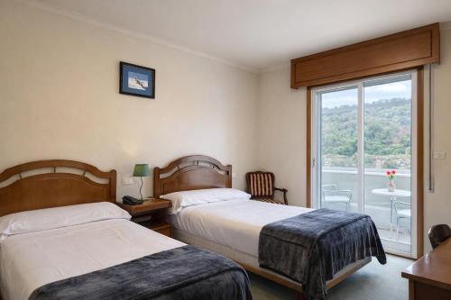 a hotel room with two beds and a window at Hotel San Rosendo in Ourense