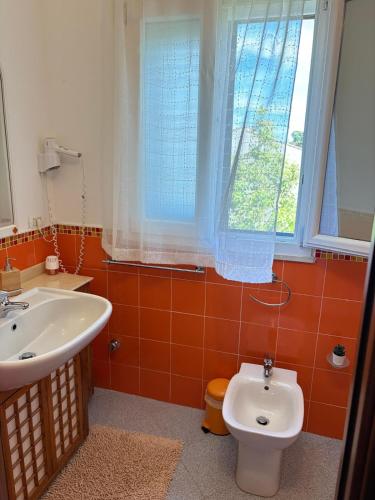 a bathroom with a sink and a toilet and a window at Sunrise in Lascari