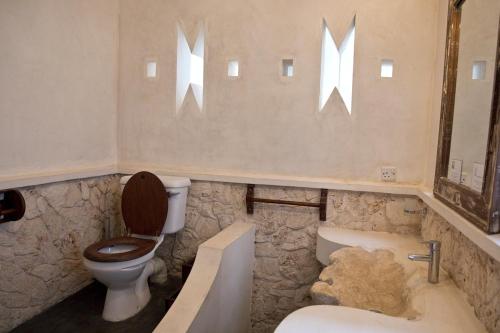 a bathroom with a toilet and a tub and a sink at Mandarina Beach House in Lamu