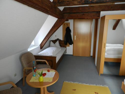 a attic room with a bed and a table and chairs at Gasthof Adler in Salem