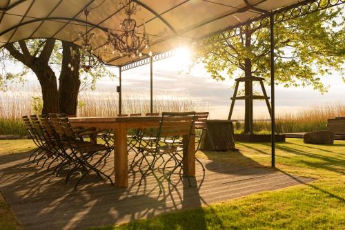 a table and chairs under a gazebo at Ferienhaus Peeneblick - exklusives Traumhaus in Direktlage am Wasser mit Bootssteg und Aussensauna in Rankwitz