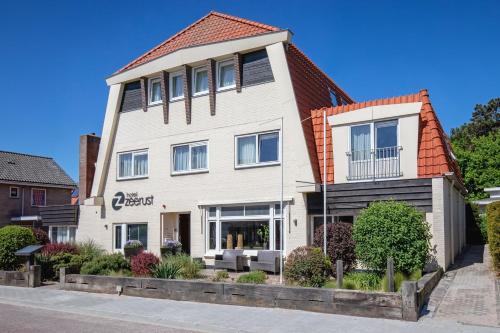 a white house with an orange roof at Hotel Zeerust in De Koog