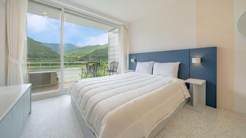 a bedroom with a large bed and a large window at Gapyeong Rowa River view Pension in Gapyeong