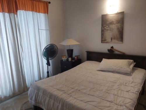 a bedroom with a bed and a fan and a window at Sun Power Villa in Hokandara South