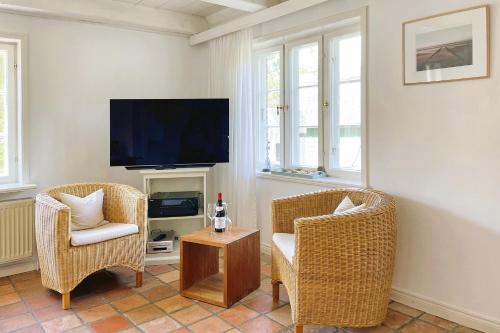 a living room with two chairs and a flat screen tv at Süderende- Hus Lillesol in Süderende