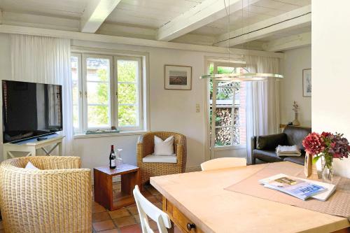 a living room with a table and a television at Süderende- Hus Lillesol in Süderende