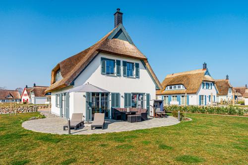 a large white house with a thatched roof at Kramerhof Rügenblick Nr 53 in Parow