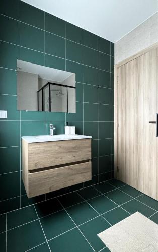 a bathroom with a sink and a mirror and green tiles at S'apartments New in Leiria