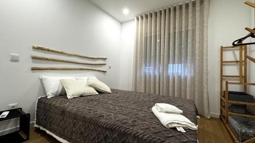 a bedroom with a bed with white pillows and a window at S'apartments New in Leiria