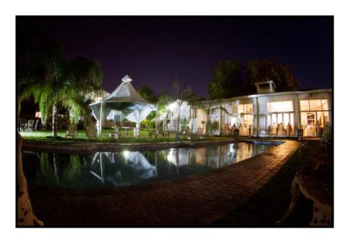 Un edificio con una piscina enfrente por la noche. en Belurana River Manor, en Upington
