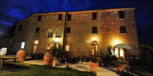 a large brick building at night with lights on at Albergo La Foresteria in Bettolle