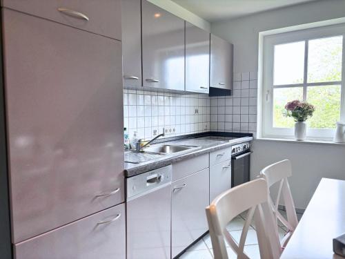 a kitchen with white cabinets and a sink and a table at Frederick Brückenblick in Wulfen auf Fehmarn