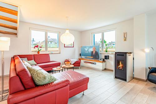 a living room with a red couch and a tv at Kramerhof Ferienhaus Luv und Lee in Parow