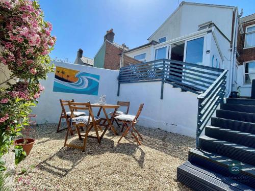a patio with a table and chairs in front of a house at Harvest Moon - cottage close to harbour in Weymouth
