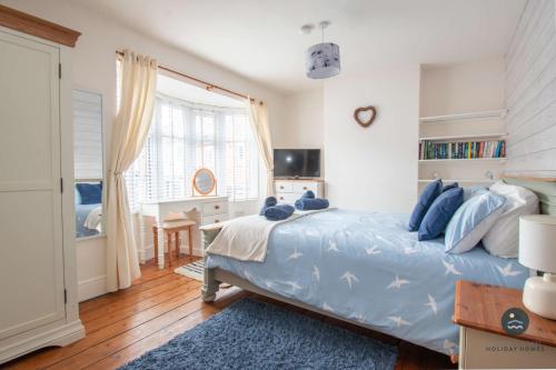 a bedroom with a blue bed with a desk and a window at Harvest Moon - cottage close to harbour in Weymouth