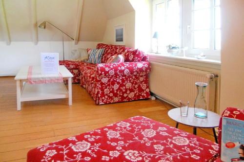 a living room with a red couch and a table at Midlum- Peppin, OG in Midlum