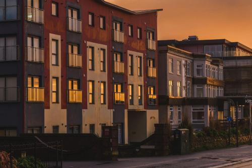 a group of apartment buildings with the sun setting at Panoramic Sea-View Family Appartment , Free Parking, Sleeps 6 , Walk to Beach, Station, & Town in Newquay