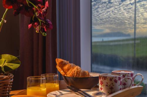 a table with a bowl of bread and a bowl of orange juice at Panoramic Sea-View Family Appartment , Free Parking, Sleeps 6 , Walk to Beach, Station, & Town in Newquay