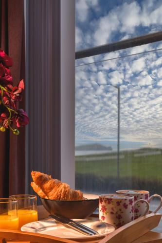 a table with a bowl of bread and a window at Panoramic Sea-View Family Appartment , Free Parking, Sleeps 6 , Walk to Beach, Station, & Town in Newquay