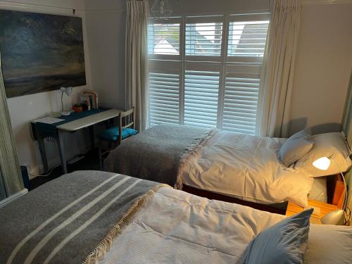 a bedroom with two beds and a desk and a window at The Artist's house in Oxford