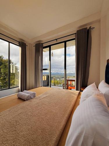 a bedroom with a large bed and large windows at Climax View Point Inn in Bandarawela