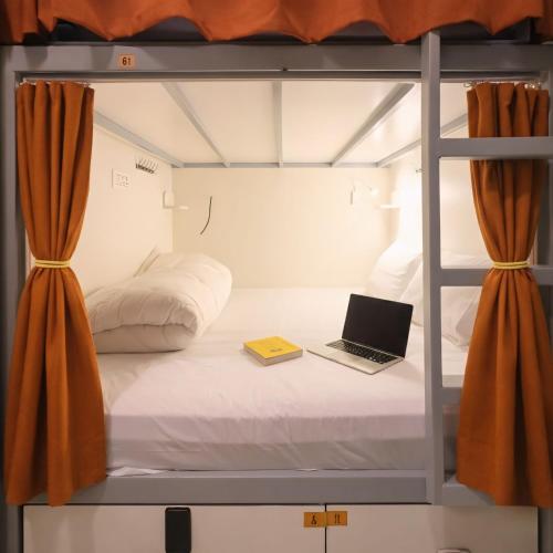 a bed in a room with a laptop on it at Metro POD Hotel at New Delhi Metro & Railway Station in New Delhi
