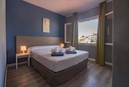 a bedroom with a bed with two towels on it at Aparthotel Nelva Resort in Cala en Porter