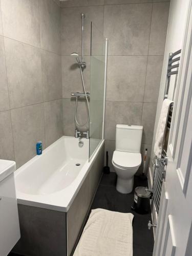 a bathroom with a bath tub and a toilet at Rooms in Islington in London