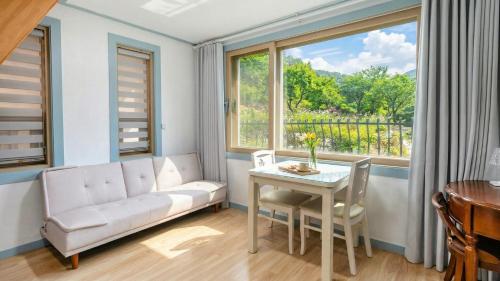 a living room with a couch and a table and a window at Gapyeong Maplein Pension in Pocheon