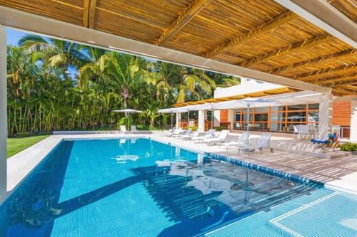 a swimming pool with chairs and a house at Villa Buho in Punta Mita in Punta Mita