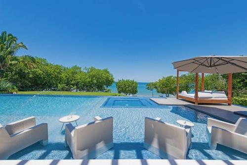 a pool at a resort with chairs and an umbrella at Villa Brisa in Punta Mita in Punta Mita