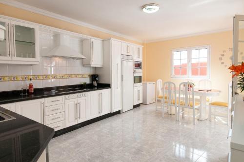 a kitchen with white cabinets and a table and chairs at Sol y Mar El Salobre in Maspalomas