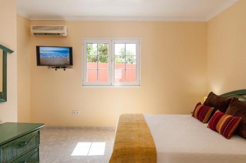 a bedroom with a bed and a tv on the wall at Sol y Mar El Salobre in Maspalomas