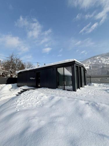 a black house in the snow in the yard at Grey House in Kvasy