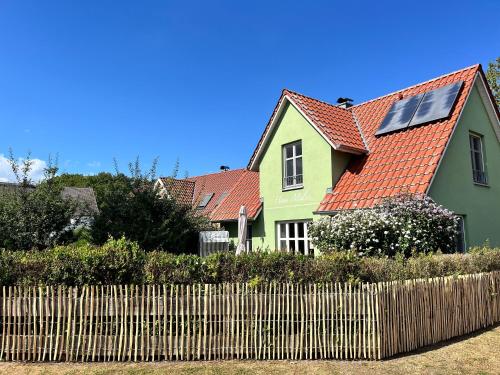 a green house with a red roof behind a fence at Ferienhaus Malve in Liepe