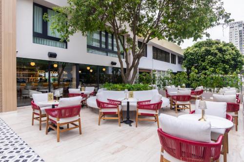 a restaurant with white tables and red chairs at Berthas Collection By EM Hotels in Cartagena de Indias