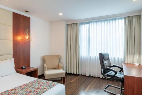 a hotel room with a bed and a chair at Hotel Andes Plaza in Bogotá