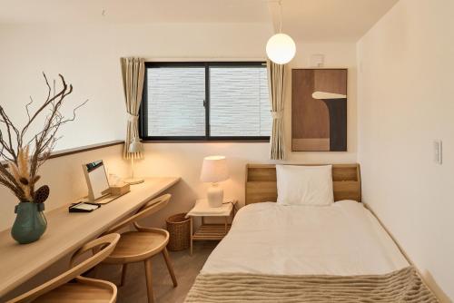 a bedroom with a bed and a desk and a window at 宿 花甜 in Osaka