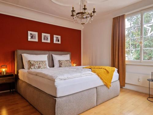 a bedroom with a large bed and a chandelier at FEWOCASA Central Family Apartment Rorschach - Lake Constance - Near St Gallen in Rorschach