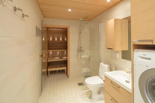 a bathroom with a toilet a sink and a washing machine at Gella Munkkisaarenkatu 2 in Helsinki