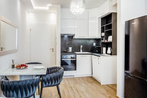 a kitchen with white cabinets and a table and chairs at Rebany Apartman 2 Free parking, Central Location in Debrecen