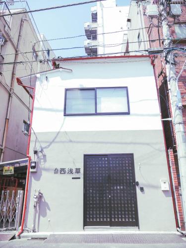 a white building with a door in a street at 9Stay西浅草 in Tokyo