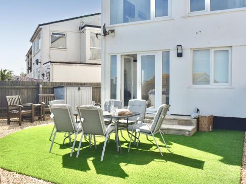 a patio with a table and chairs on grass at Seagulls View in Brixham