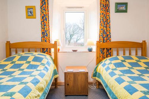 two beds in a room with a window at 1 Caerau Isaf in Haverfordwest