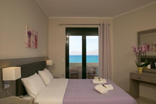 a bedroom with a bed and a view of the ocean at Christina Beach Hotel in Kissamos