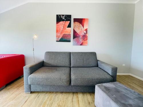 a living room with a couch and paintings on the wall at Apartment Rickmer Rickmers Teichhof Fehmarn in Wenkendorf